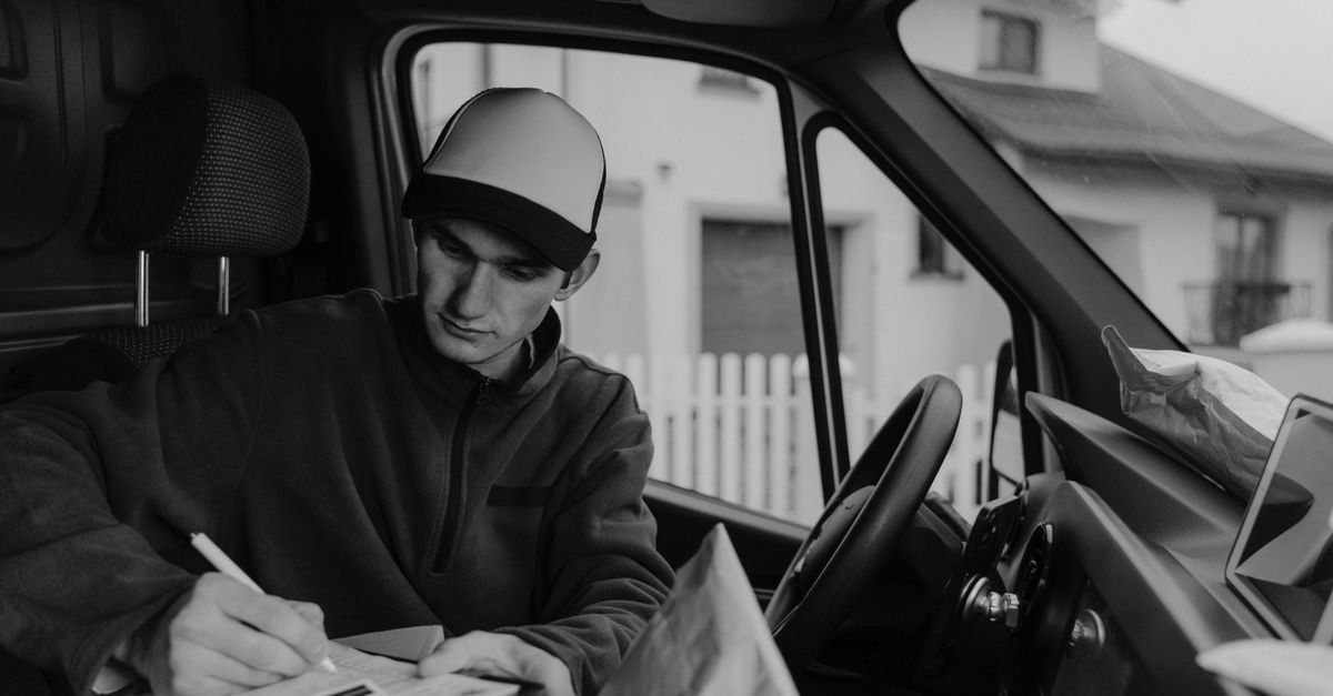 Black-and-white photo of a delivery driver organizing packages in a van.