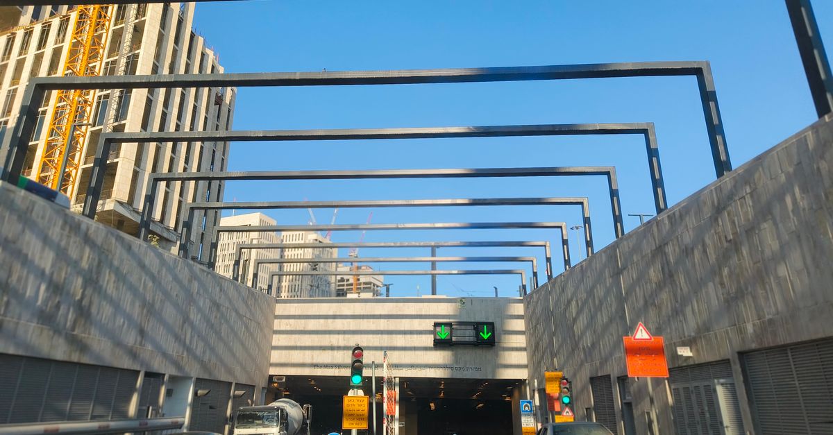 Dynamic urban scene with traffic entering a tunnel beneath modern buildings.